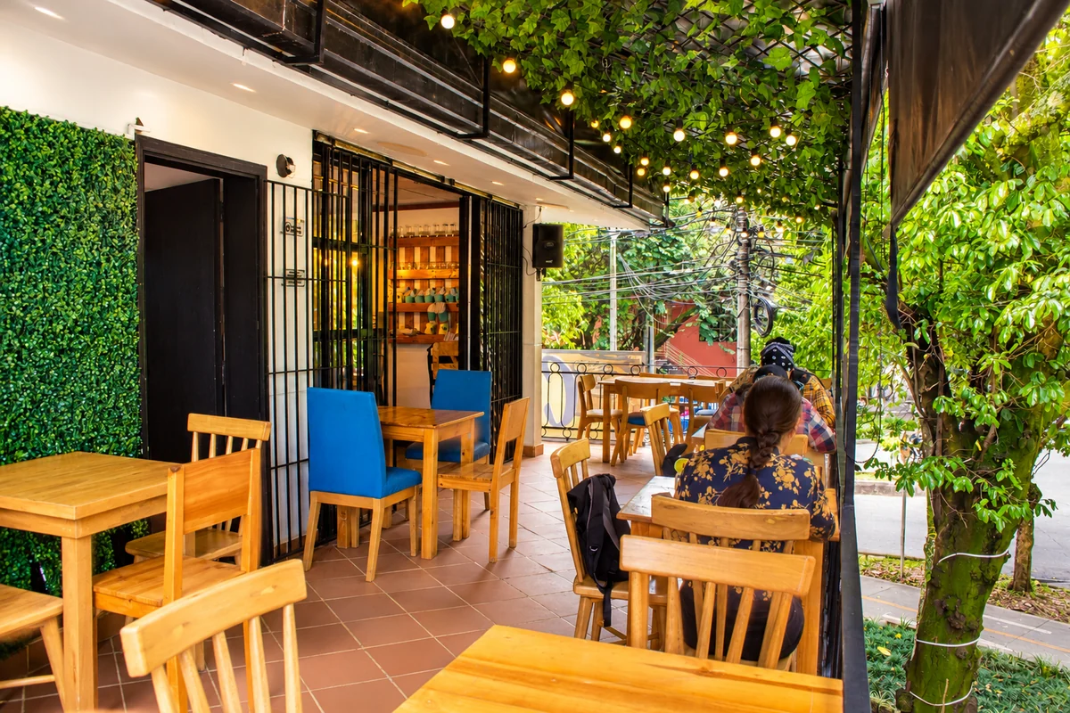 Terraza de Tepuy Laureles con mesas de madera y árboles